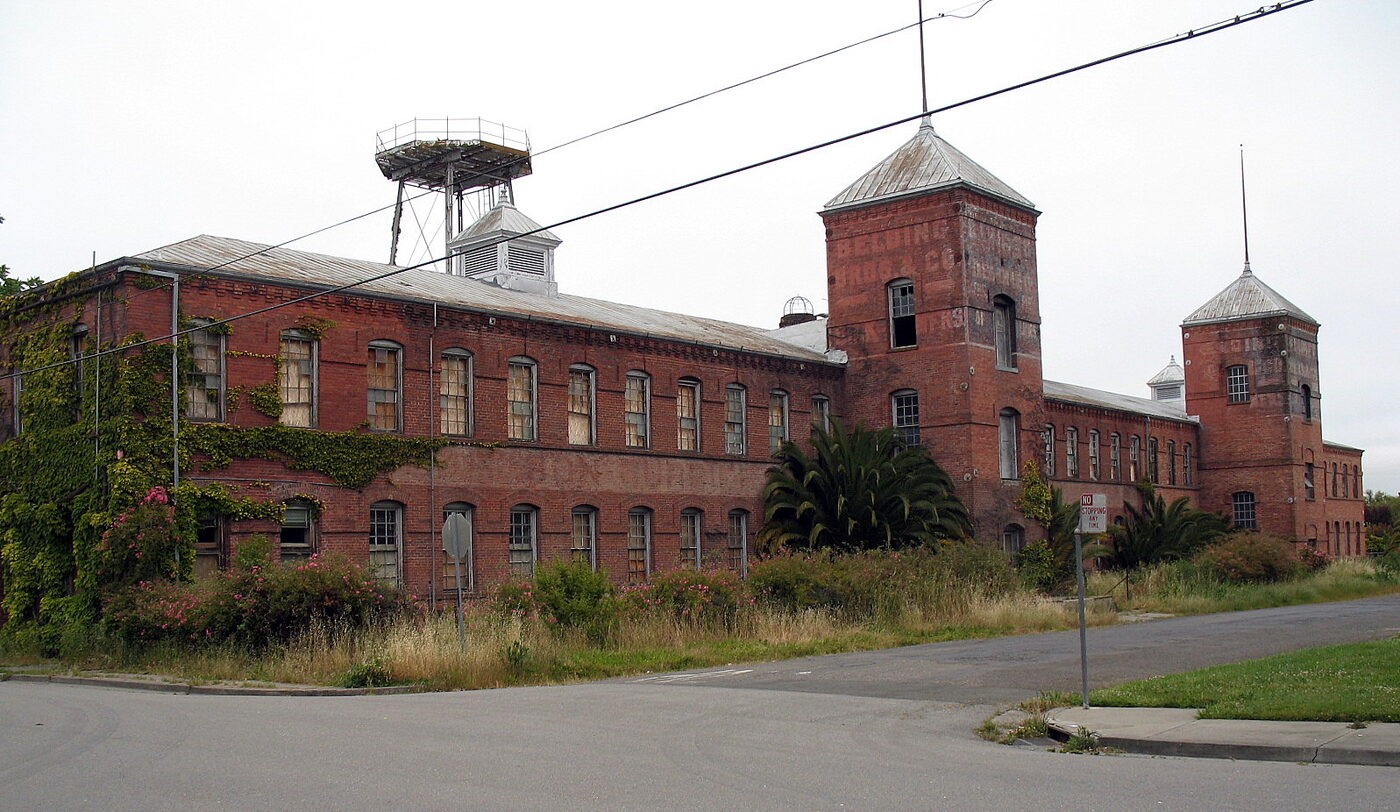 The two-story red-brick Petaluma Silk Mill with its twin square brick towers and rooftop water-tower frame, ivy climbing the walls.